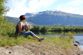 Dame med blomterbukett ved elva